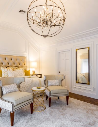 Elegant bedroom with a classic design featuring a tufted headboard, herringbone wood floor, and a modern chandelier.